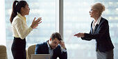 Mad middle aged businesswoman have dispute with young Asian employee blaming for mistake in documents, female partners conflict arguing at business meeting, accusing in contract failure